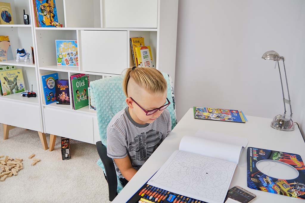 chłopczyk wybiera kolorowankę siedząc przy biurku