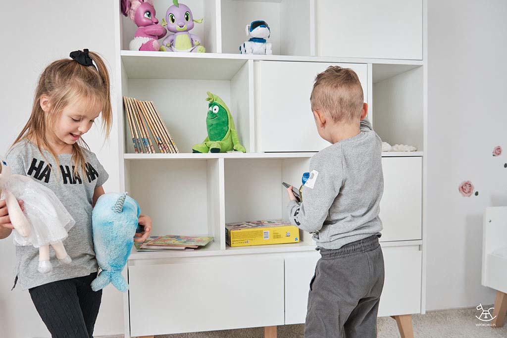 dziewczynka i chłopiec układają zabawki na regale
