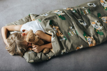 chłopiec śpi w ocieplanym śpiworze z motywem safari