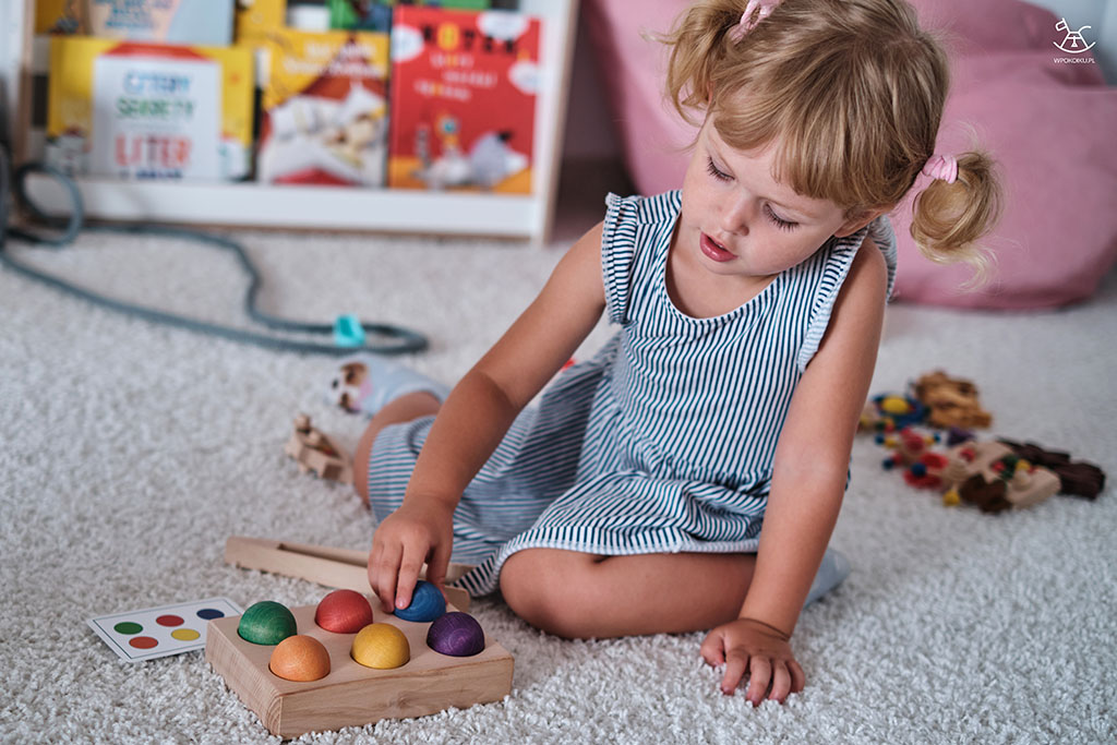 dziecko układa drewniane kulki według schematu