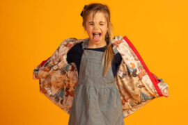 dziewczynka wytyka język rozkładając przy tym kurteczkę w fantazyjne wzory na boki