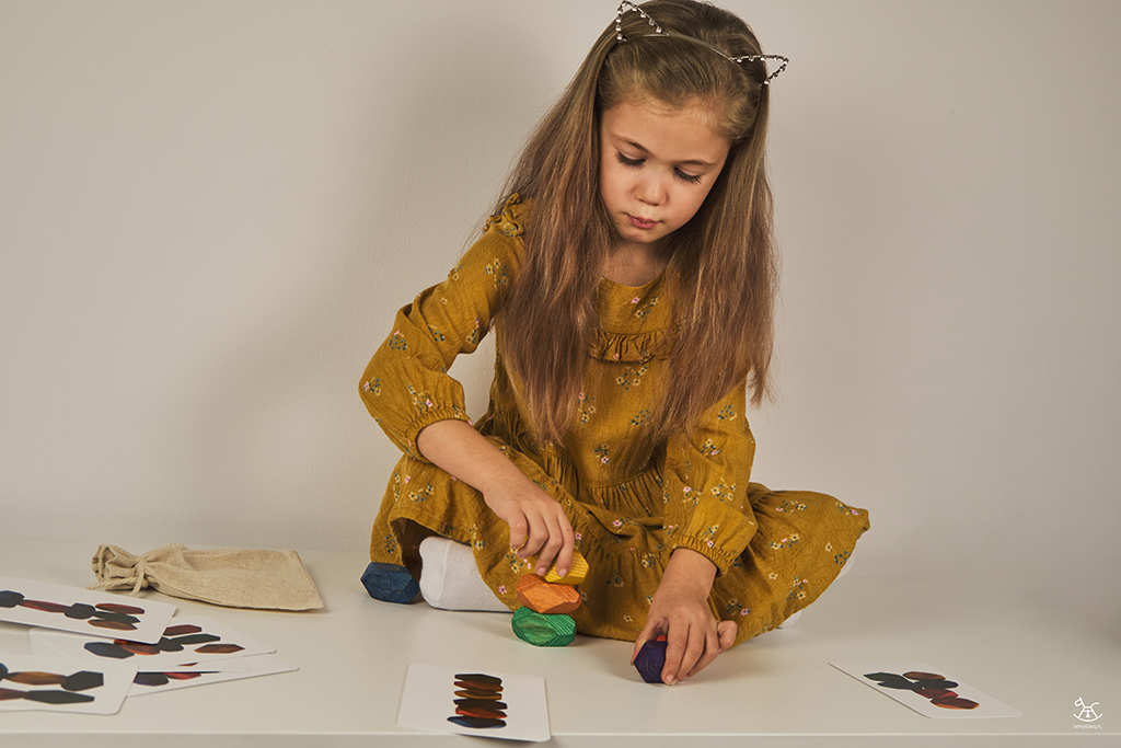 dziewczynka układa kamyki balansujące według wzoru z karty
