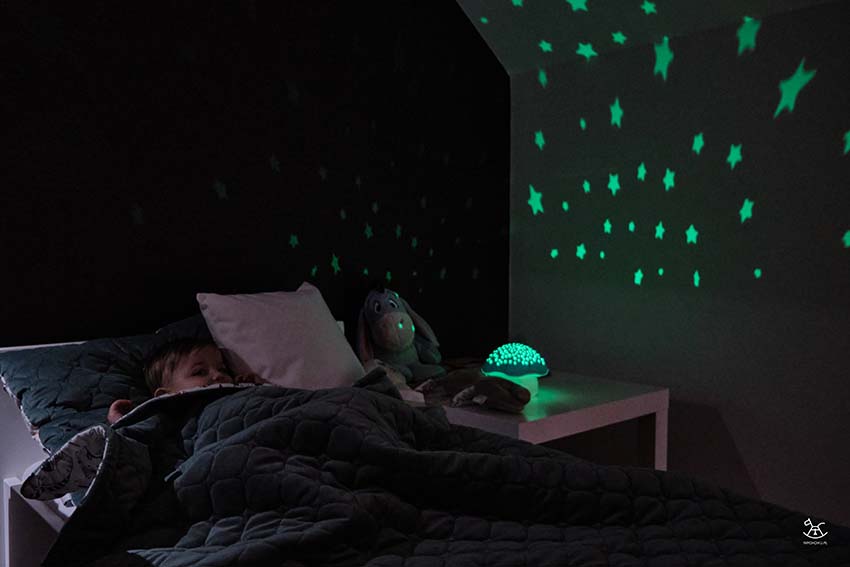 dziewczynka ułożona do snu z włączonym projektorem grzybkiem